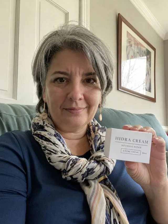 Cliente segurando a caixa do Hidra Cream em casa